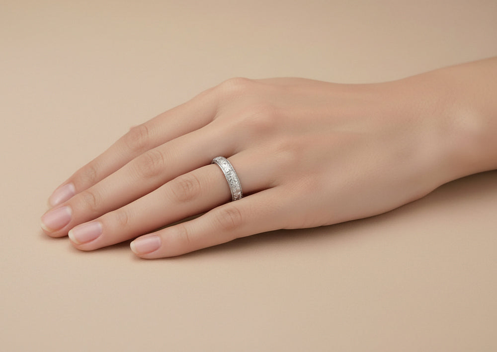 Ladies hand with a 3.5mm wide 1920s Art Deco vintage wedding ring in platinum with a carved floral pattern - R853P.