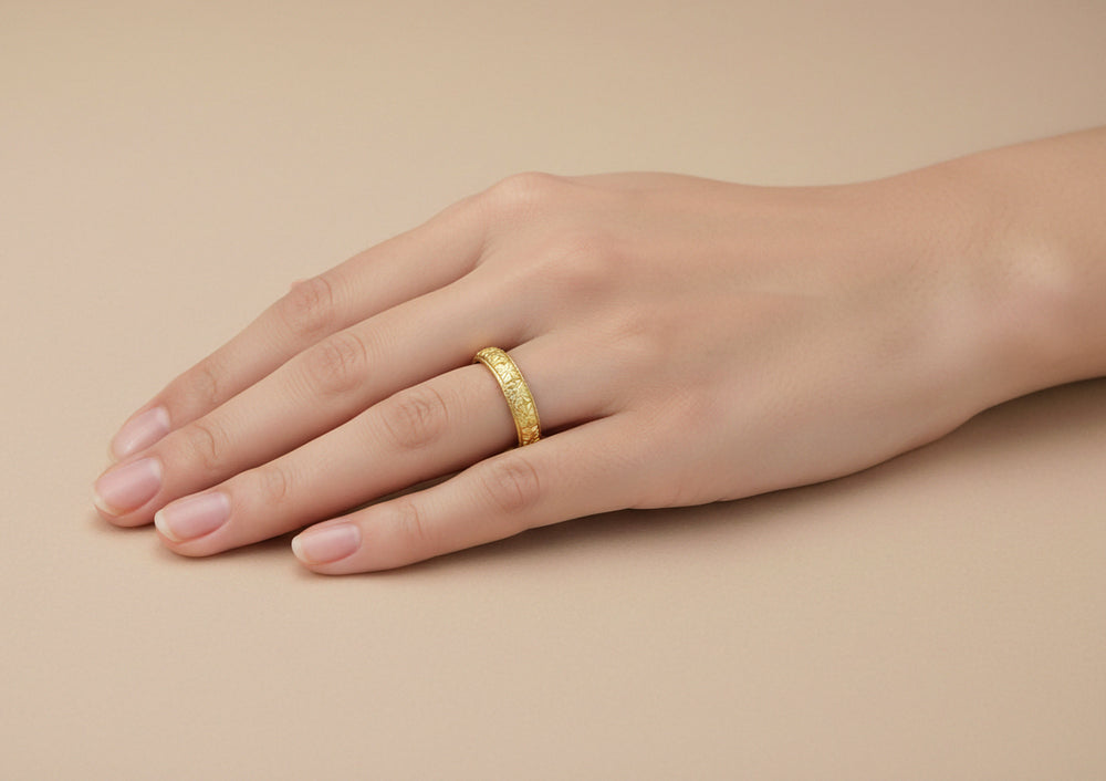 Woman's hand wearing a 3.5mm wide yellow gold Art Deco wedding ring with floral carved pattern - R853Y