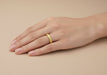Woman's hand wearing a 3.5mm wide yellow gold Art Deco wedding ring with floral carved pattern - R853Y