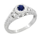 An Art Deco filigree sapphire engagement ring with a round brilliant cut natural royal blue sapphire center stone, in a hexagon frame, surrounded  by round brilliant cut diamonds on the sides, set in your choice of 14 karat or 10 karat white gold.
